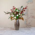Artificial rose and berry arrangement with autumn foliage in a tall bronze geometric pot.