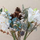 Close up of Artificial Amaryllis, Pine Cone & Eucalyptus Arrangement with white amaryllis blooms, brown pine cones, frosted winter foliage and eucalyptus