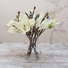 Artificial cream magnolia spray stems displayed together in a vase for styling purposes