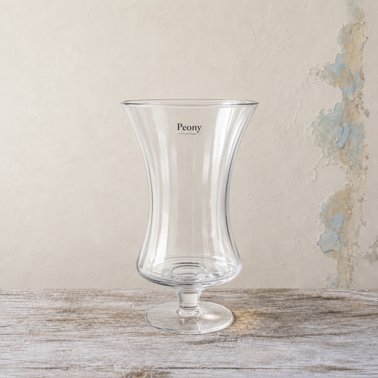 Clear waisted footed glass vase with a gently flared rim.