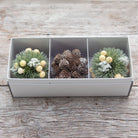 A set of three artificial Nordic hanging balls with berries and pine cones on a wooden surface.