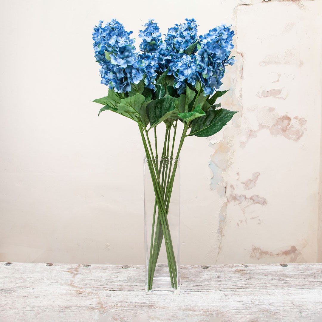 Artificial blue conehead hydrangea stems displayed together in a vase for styling purposes