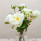Roses & ranunculas with wax flowers in a lace bottle vase with ribbon trim Peony