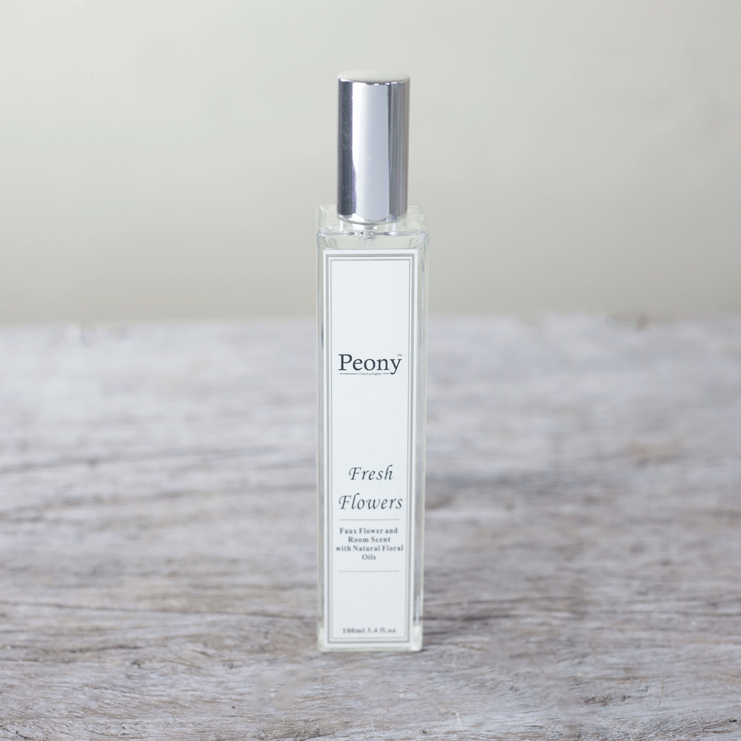 A bottle of Peony fresh flower fragrance with a white label on a wooden surface.