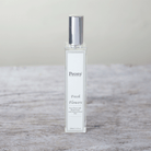 A bottle of Peony fresh flower fragrance with a white label on a wooden surface.
