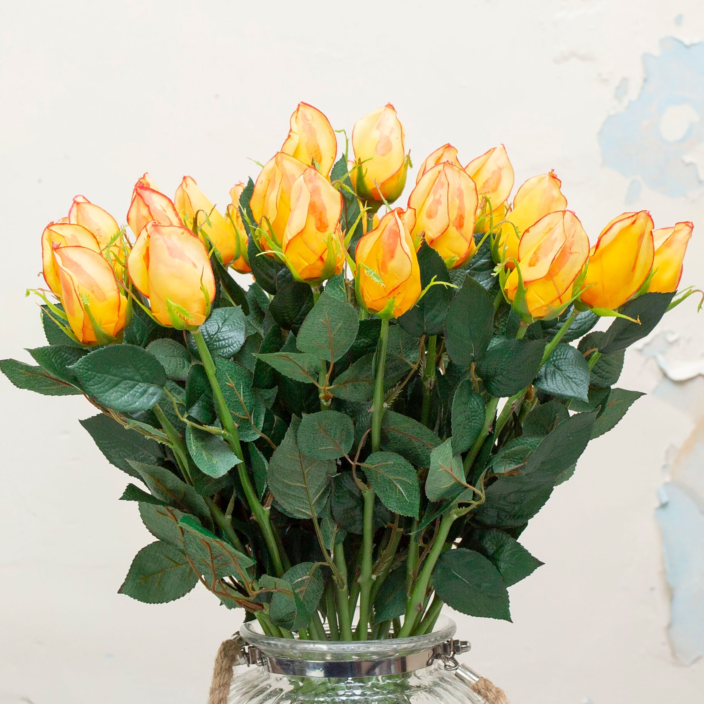 Yellow rose bud with a hint of red with leaves. Peony