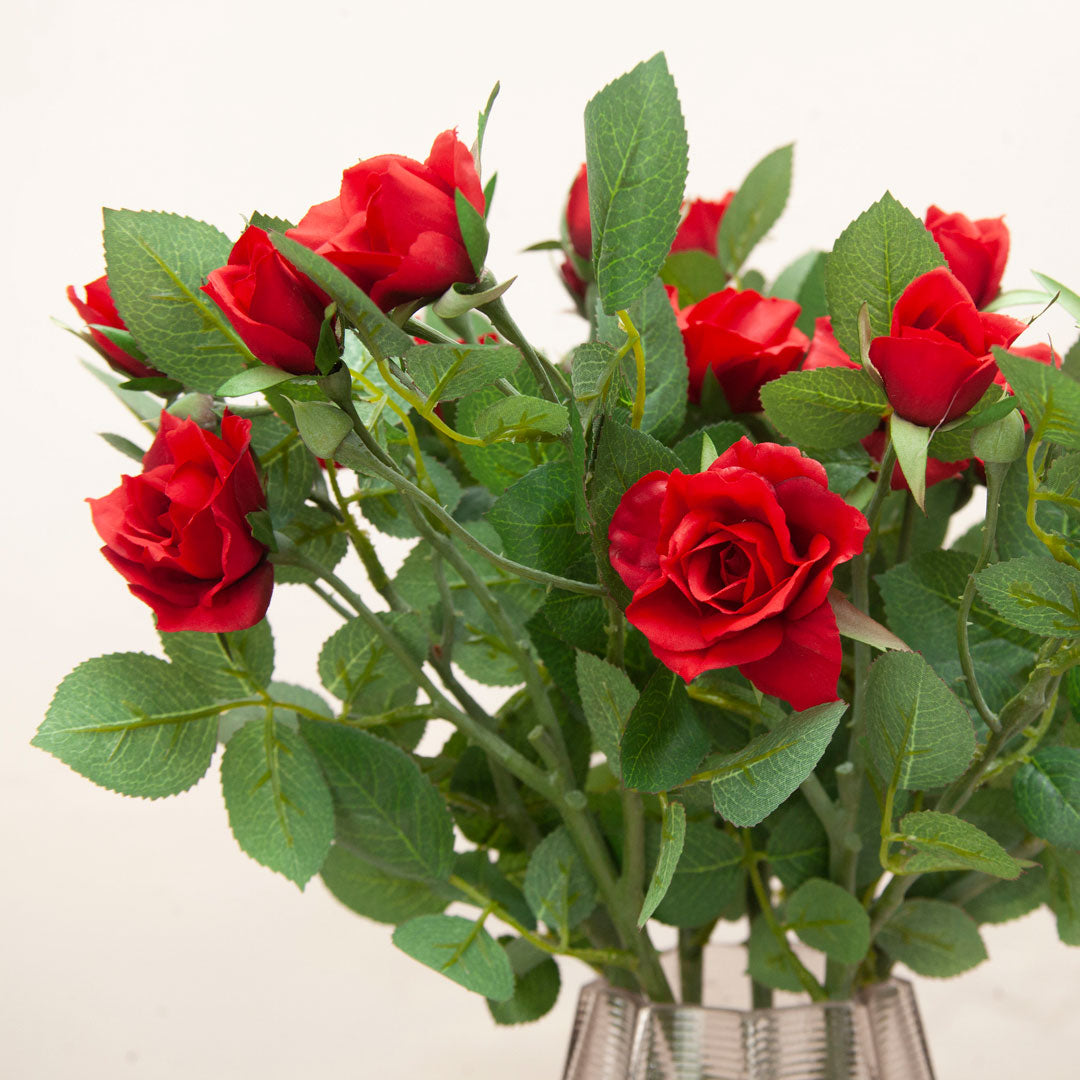 Close-up of artificial red rose bloom showing detailed petals and natural-looking leaf texture.