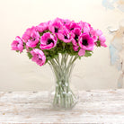 A clear glass vase displaying  the pink anemone stems with dark centers, for styling purposes