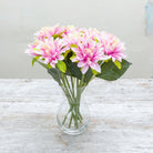 Artificial pink dahlia stems displayed in a glass vase
