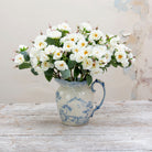 Artificial white rose spray stem displayed in a vase, showcasing softly opened white roses, layered petals and natural green leaves