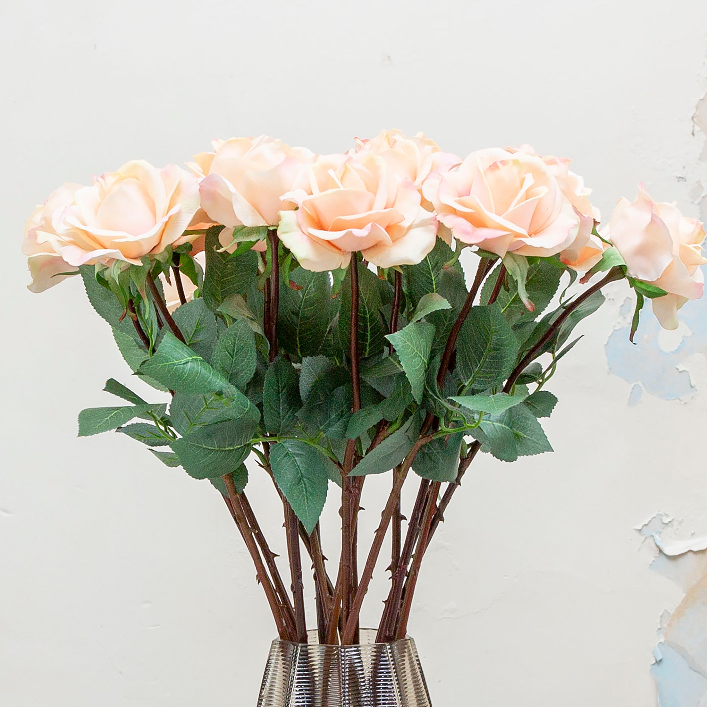 Close-up of artificial rose flower, showing soft peach petals with blush-pink edging, layered petal detail and realistic texture.”