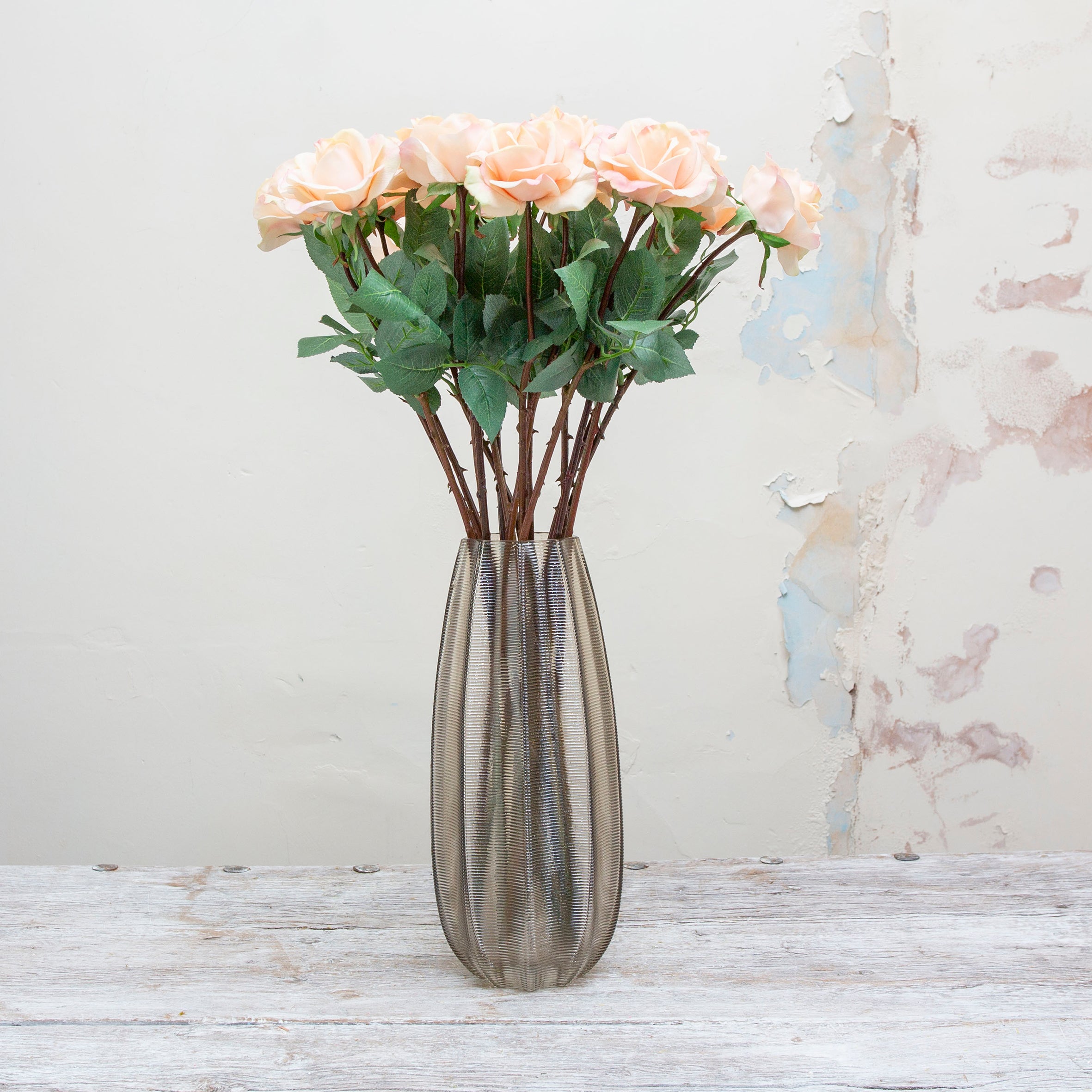 Artificial peach and blush-pink rose stem displayed in a vase, showcasing a gently open rose flower with natural colour variation and lifelike leaves.