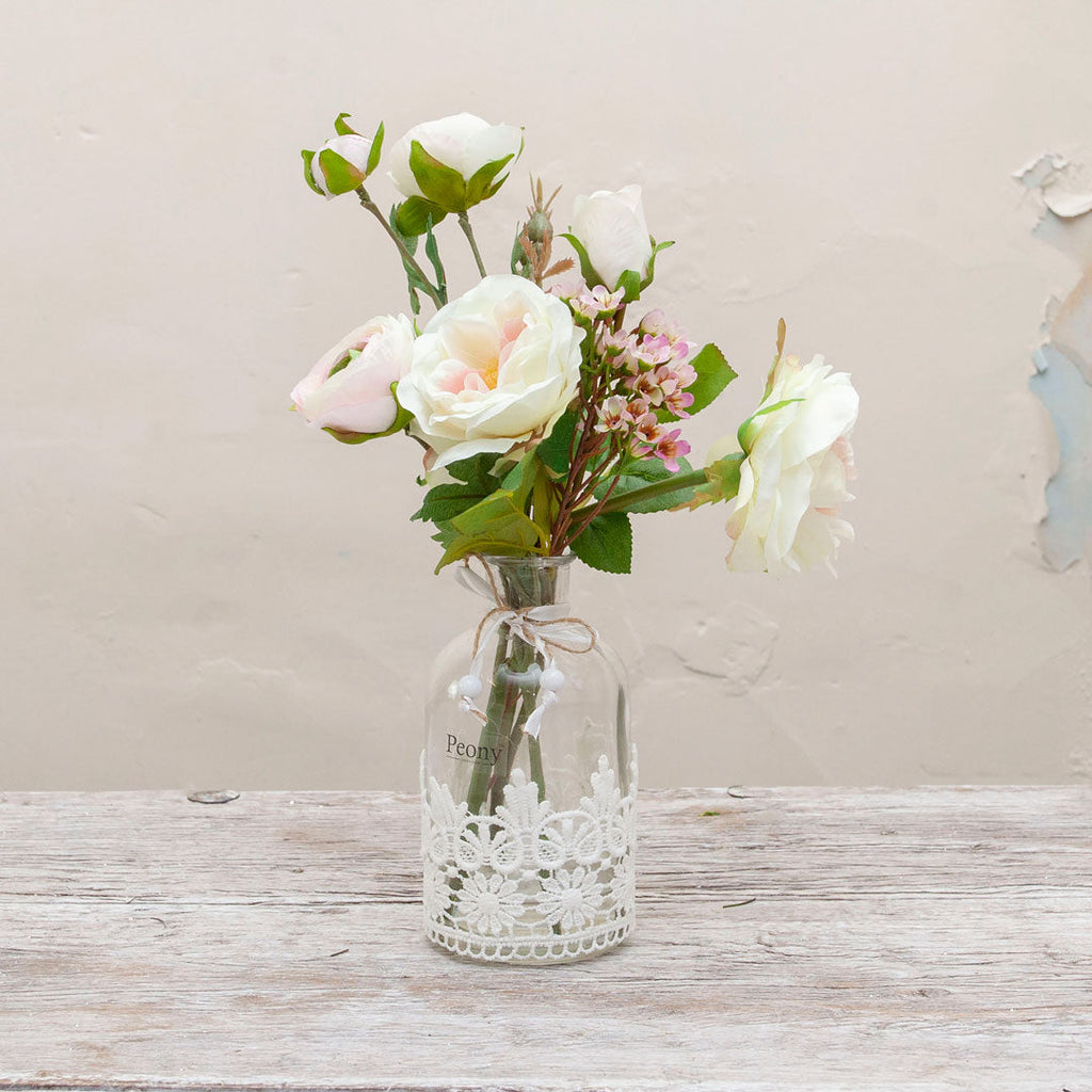 Roses and ranunculas with wax flowers in the lace bottle vase  Peony